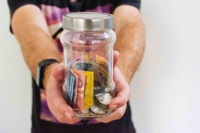 person holding clear glass jar filled with money